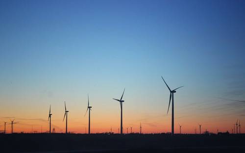 Solar panels and wind turbines in Alberta field with a modern business team