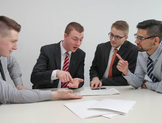A diverse group of professionals in a modern office discussing business finances with Canadian documents