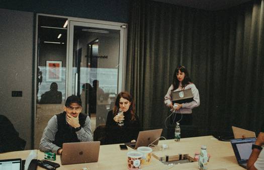 A diverse Canadian startup team collaborating in a modern workspace, with laptops and whiteboard brainstorming