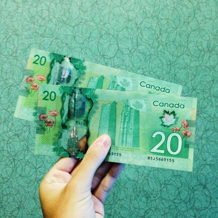 A closeup of a Canadian tax refund cheque and a person smiling with financial documents