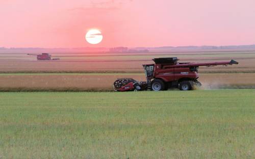 Manitoba farm field with modern agriculture equipment at sunrise