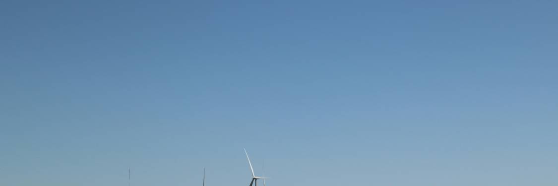 Modern wind farm and solar panels in Manitoba with blue sky and green fields, representing clean tech business