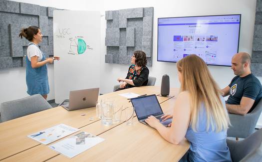 Ontario innovation lab with a diverse research team collaborating, computers open, and digital project on screen